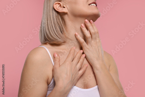 Woman touching her neck on pink background  closeup
