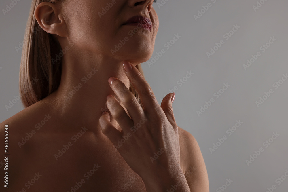 Woman touching her neck on grey background, closeup Woman touching her neck on grey background, closeup
