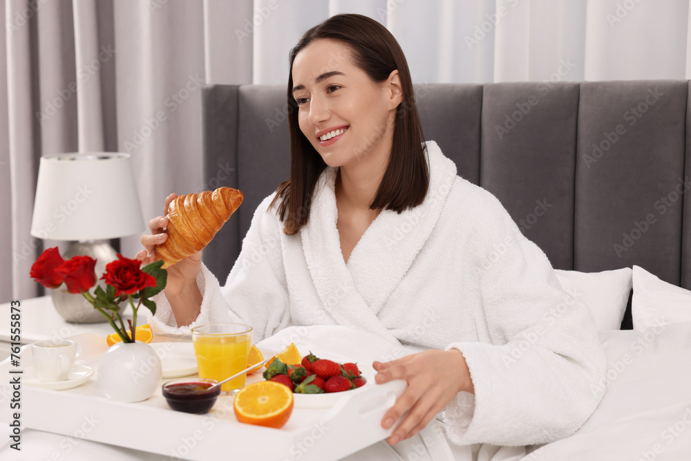Smiling woman having breakfast in bed at home Smiling woman having breakfast in bed at home
