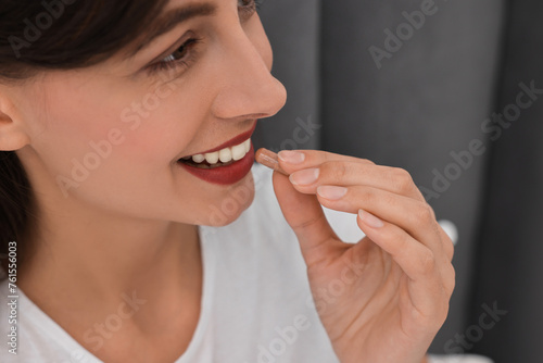 Beautiful woman taking vitamin pill at home, closeup