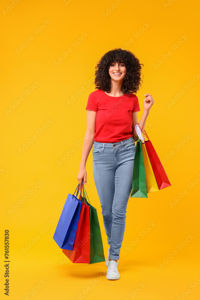 Happy young woman with shopping bags on yellow background Happy young woman with shopping bags on yellow background