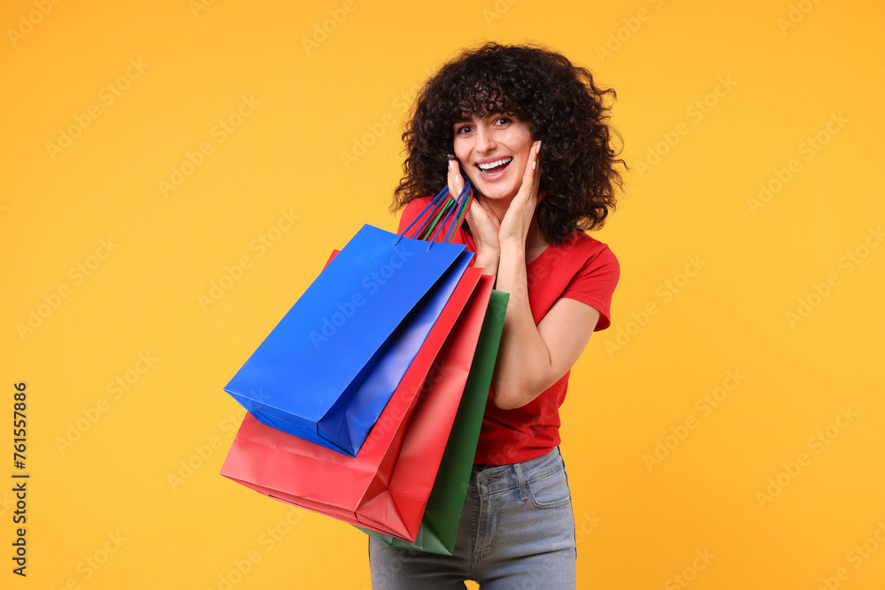 Happy young woman with shopping bags on yellow background Happy young woman with shopping bags on yellow background