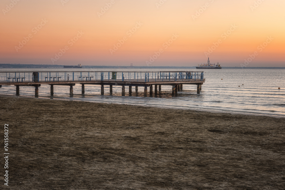 Empty sandy beach with observation deck with beautiful views of the calm sea and serene sky in soft morning light, scenic seascape, summer vacation and travel concept, Larnaca, Cyprus
