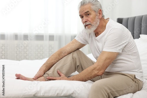 Arthritis symptoms. Man suffering from pain in leg on bed at home