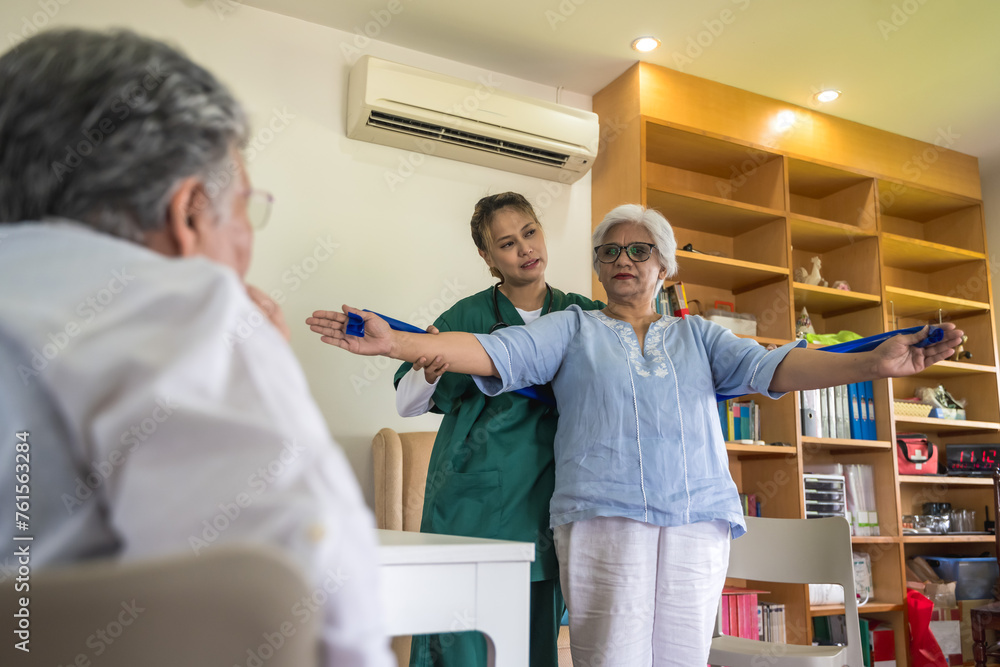Obraz premium Young friendly care taker helping elderly woman exercise in home care