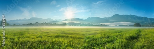 panoramic view of a foggy green meadow with mountains in the background, a blue sky, the sunny morning light Generative AI photo