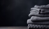 A stack of gray knitted winter sweaters on a dark background. Copy space