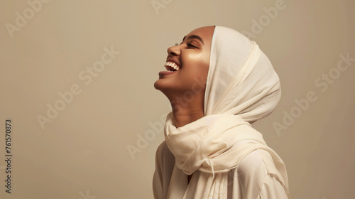 A joyful expression of freedom and happiness, captured as a woman in a white hijab laughs with her head tilted back, embodying a sense of lightheartedness and positivity