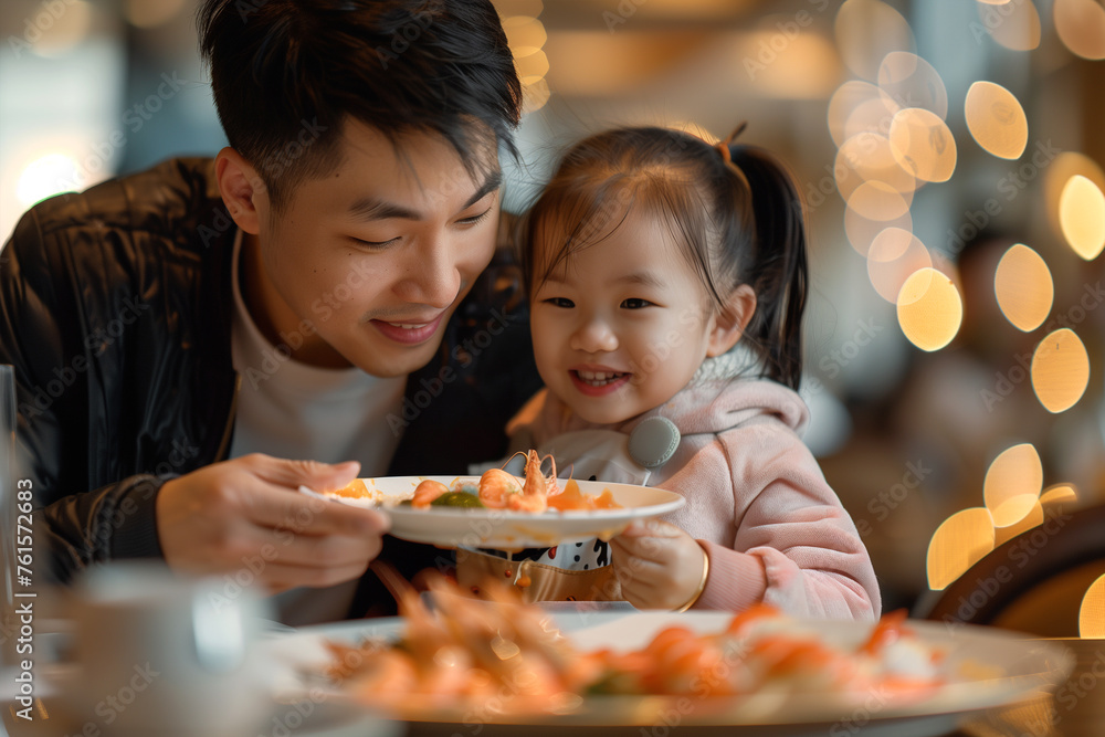 Father feeding shrimp to daughter in restaurant Father feeding shrimp to daughter in restaurant