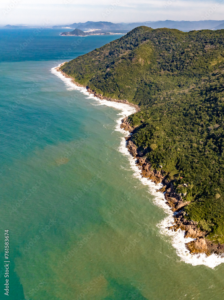 Coastline with beach, mountains and blue ocean with waves in Brazil. Aerial view of Saquinho beach. Florianopolis Santa Catarina..