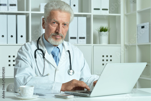 Portrait of confident senior male doctor working in office