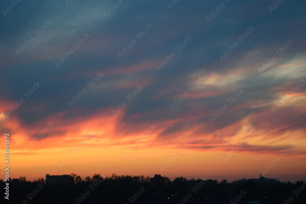 Multi-colored evening sky over a black silhouette of a forest on the horizon