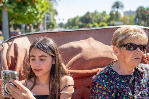 Happy elderly reitred woman riding a horse carriage with her grand daughter photo