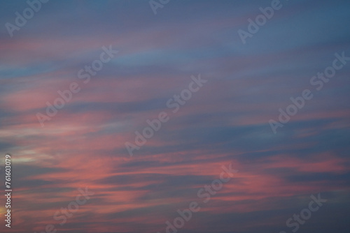 Stunningly beautiful multi-colored violet-pink-lilac evening sky with the yellow light of the setting sun, multi-colored clouds spreading from the lower horizon
