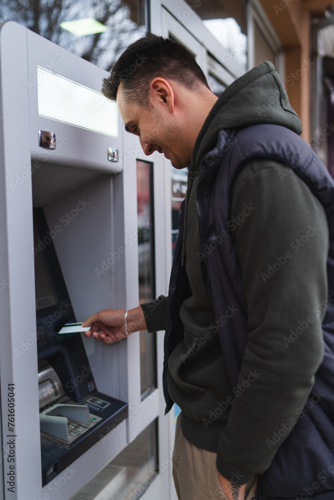 A one young man withdrawing money on ATM with credit card in the city A one young man withdrawing money on ATM with credit card in the city