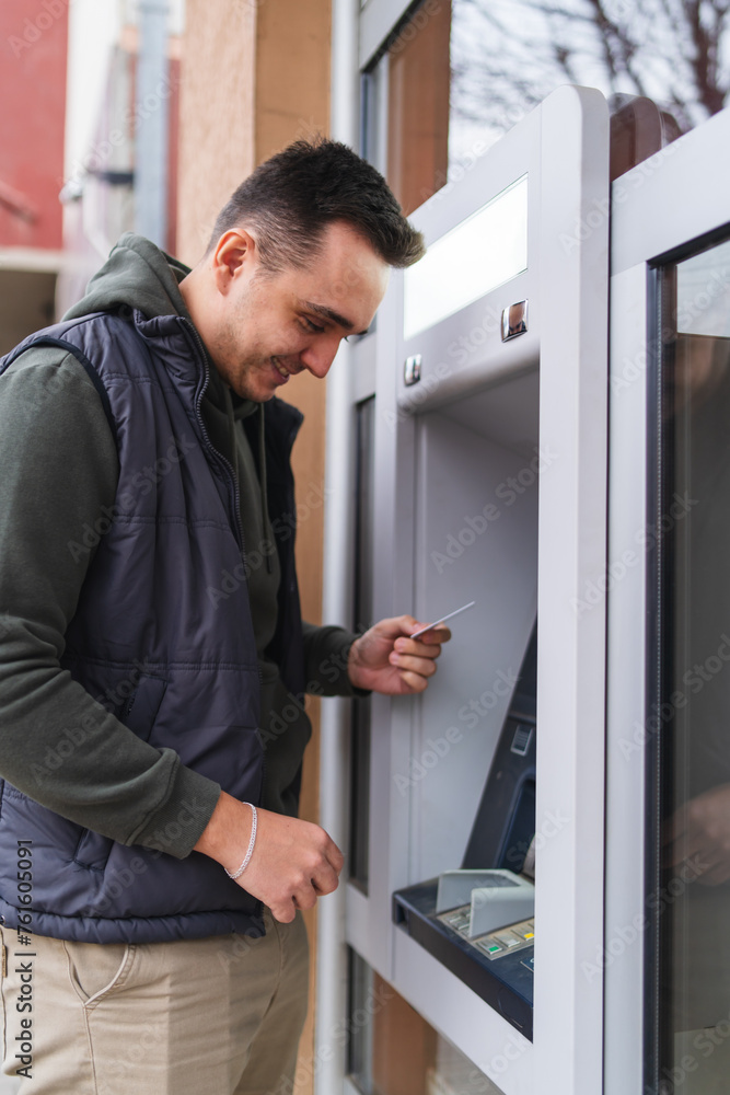 A one young man withdrawing money on ATM with credit card in the city A one young man withdrawing money on ATM with credit card in the city