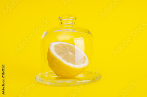 Sliced fresh lemon in glass case on yellow background