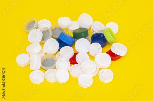 Pile of plastic caps from soda bottle on a yellow background
