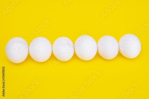 Row of chicken eggs on a yellow background