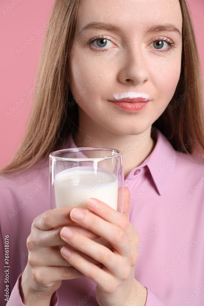Cute woman with milk mustache holding glass of tasty dairy drink on pink background Cute woman with milk mustache holding glass of tasty dairy drink on pink background
