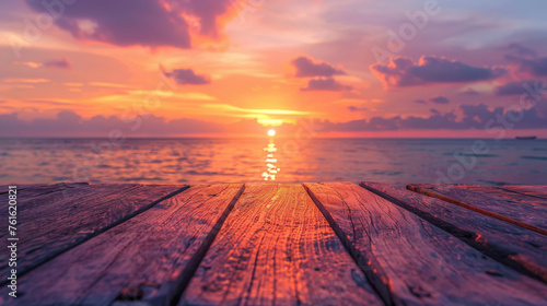 Warm sunset over tranquil ocean viewed from weathered wooden dock, evoking peace and serenity.