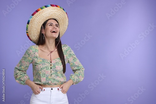 Young woman in Mexican sombrero hat on violet background. Space for text