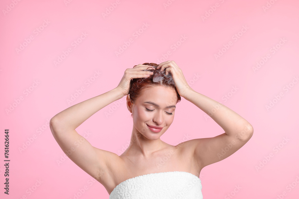 Happy young woman washing her hair with shampoo on pink background Happy young woman washing her hair with shampoo on pink background
