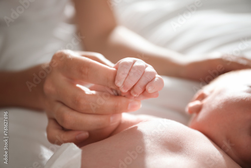 Mother with her newborn baby, closeup on hands