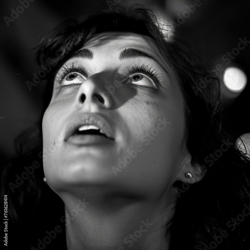 A woman looking up with her eyes wide open  which could suggest surprise or attentiveness