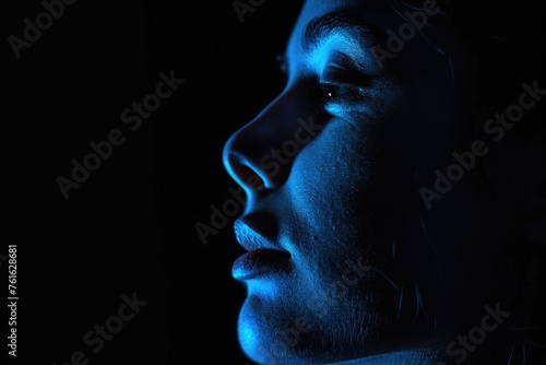 A profile of a person s face illuminated by blue light  showing a contemplative or emotional moment