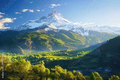 A mountain range with snow on the top and a green valley below photo