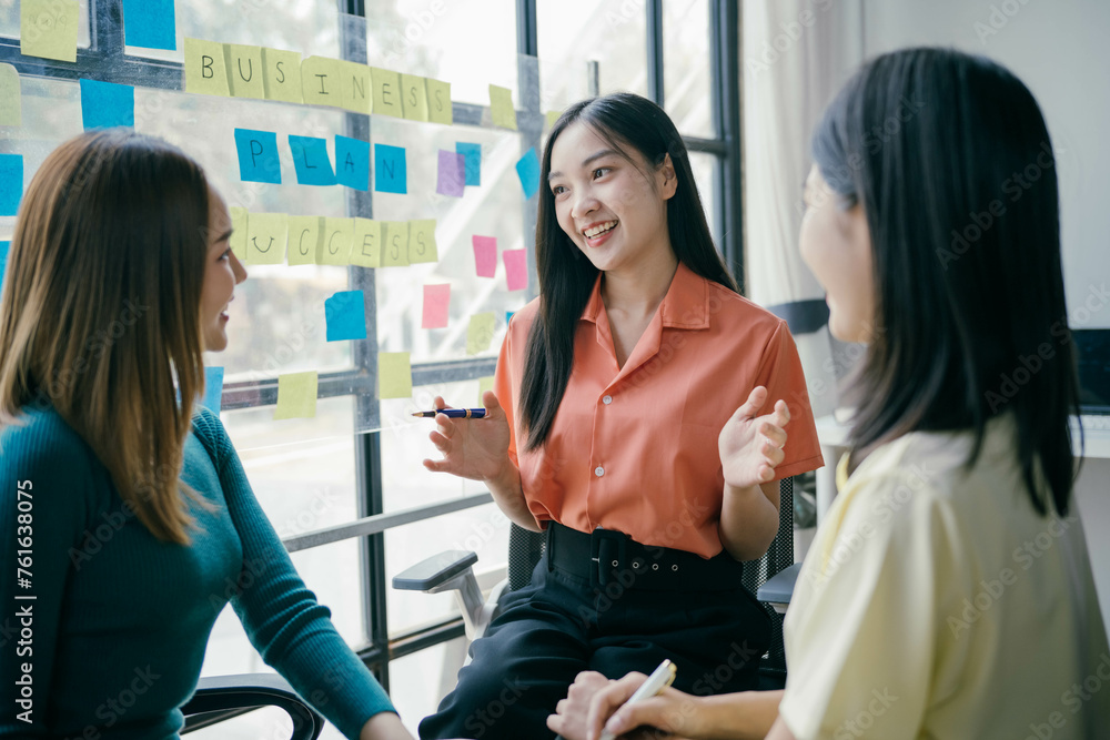 Three women are sitting together in a room with a whiteboard behind them Three women are sitting together in a room with a whiteboard behind them
