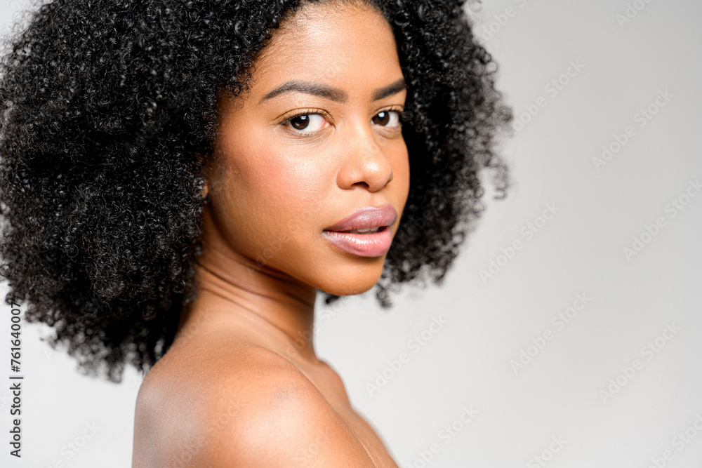 With a turn of her head and a subtle gaze, African-American woman exudes a quiet strength and refined beauty, complemented by her voluminous curly hair and the simplicity of the backless bra With a turn of her head and a subtle gaze, African-American woman exudes a quiet strength and refined beauty, complemented by her voluminous curly hair and the simplicity of the backless bra