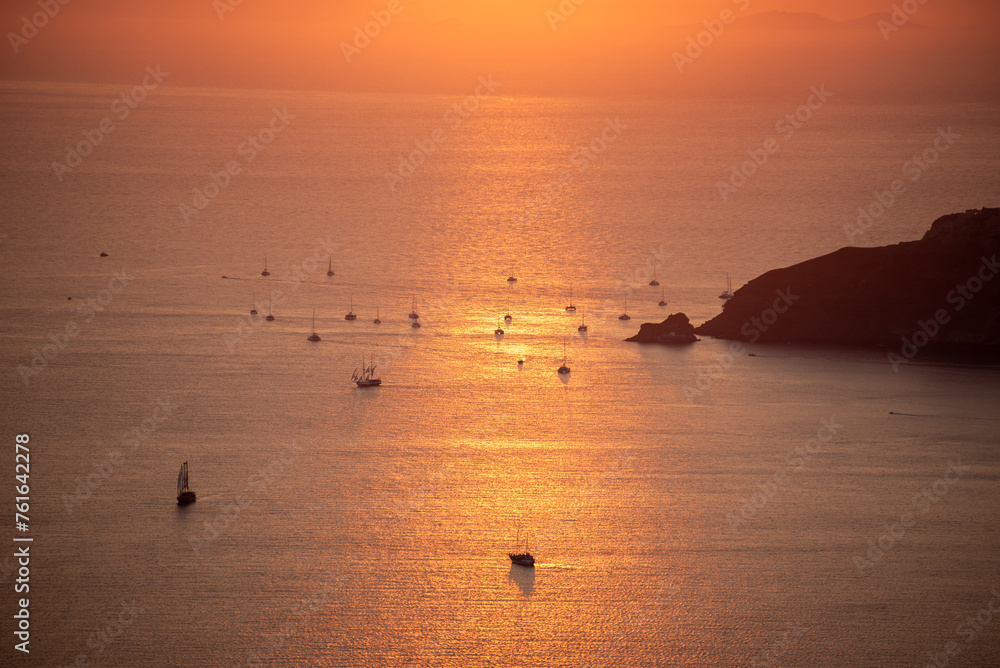 A shot of sunset over caldera in Santorini. Sailboats and catamarans on the water...