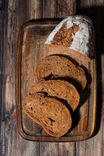 sliced rye bread on a wooden cutting board, vertical top view © cook_inspire