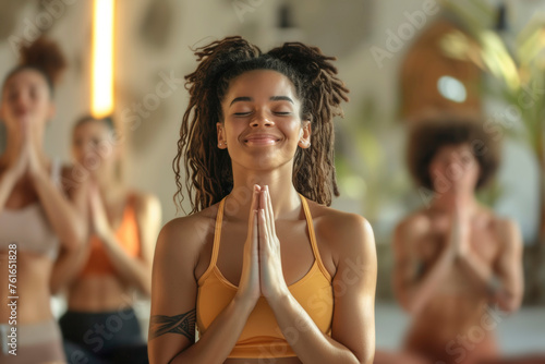 Group yoga and meditation class promotes fitness and relaxation, A woman in a yellow tank top is praying in a yoga class. The other people in the class are also praying