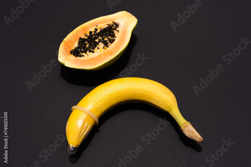 Banana with Condom and Papaya on black background. Sexual Health and Education Concept photo