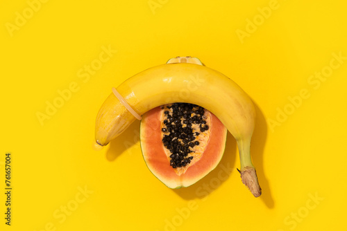 Banana with Condom and Papaya on yellow background. Sexual Health and Education Concept photo