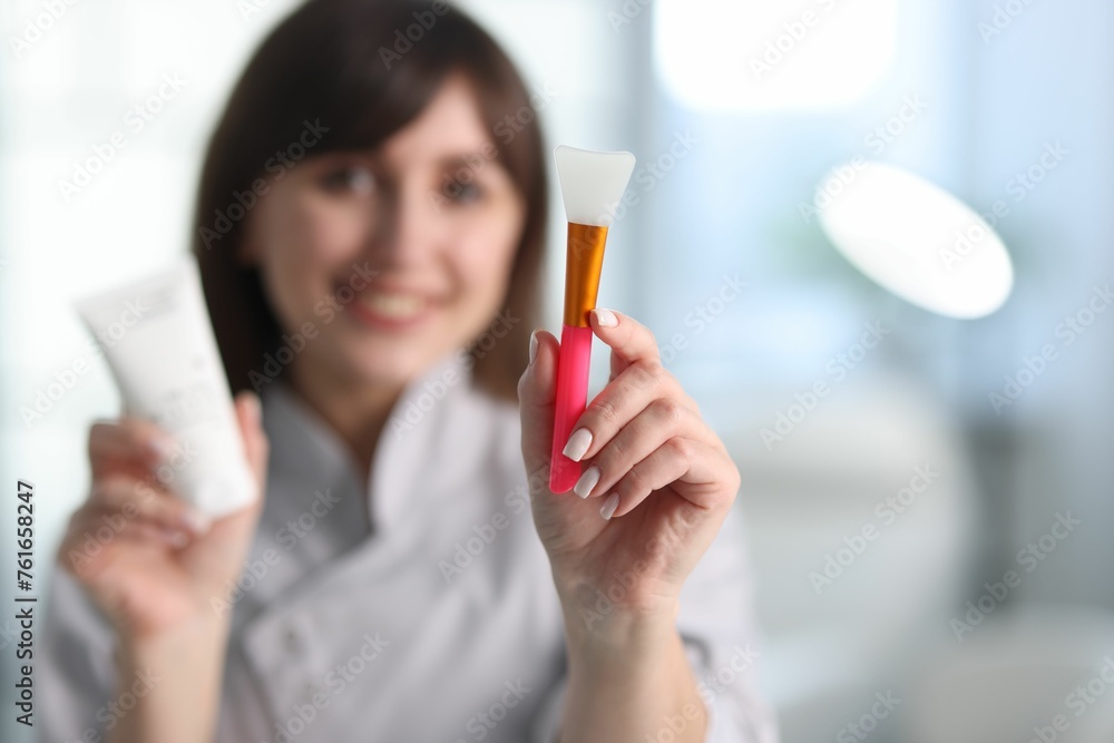 Cosmetologist with silicone brush and cosmetic product in clinic, selective focus Cosmetologist with silicone brush and cosmetic product in clinic, selective focus