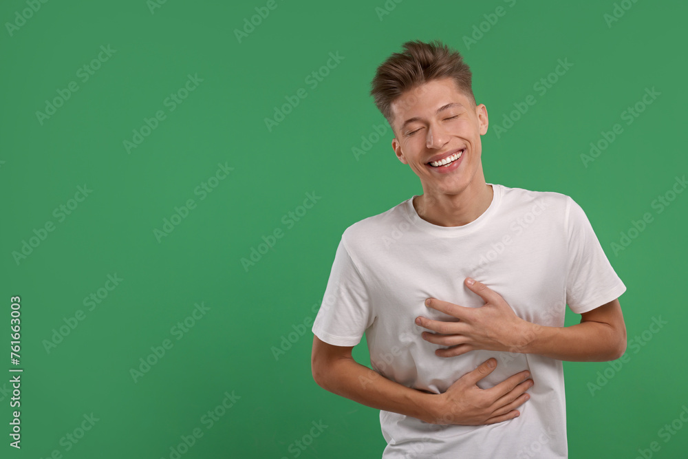 Portrait of young man laughing on green background. Space for text Portrait of young man laughing on green background. Space for text