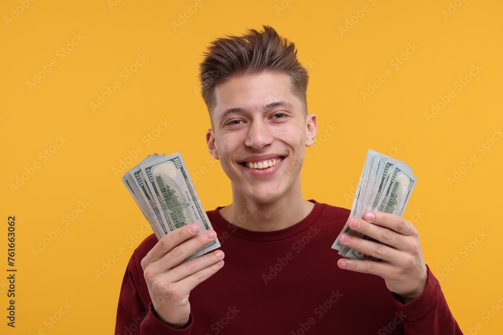 Happy man with dollar banknotes on yellow background Happy man with dollar banknotes on yellow background