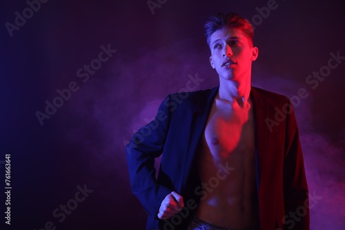 Sexy young man in neon lights with smoke effect. Space for text