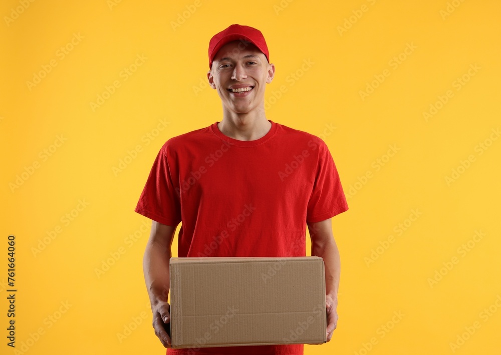 Happy courier with parcel on yellow background Happy courier with parcel on yellow background