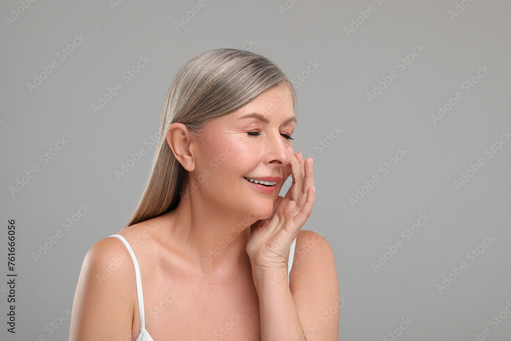 Beautiful mature woman with healthy skin on gray background, space for text Beautiful mature woman with healthy skin on gray background, space for text