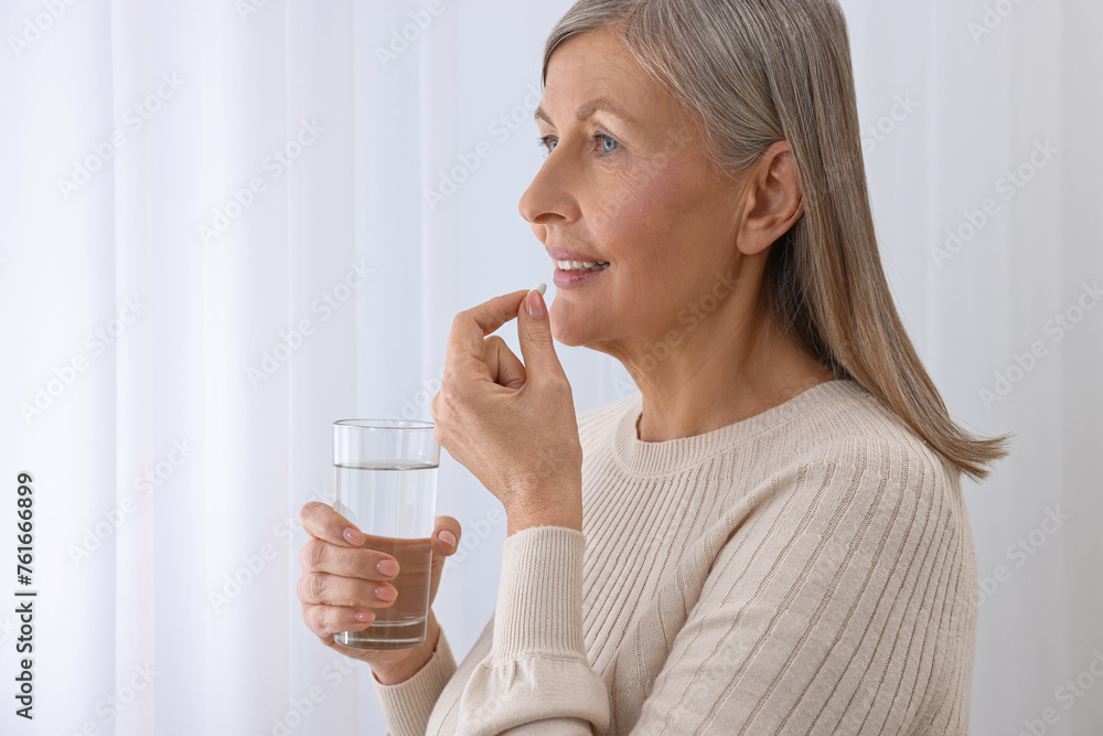 Beautiful woman taking vitamin pill at home Beautiful woman taking vitamin pill at home