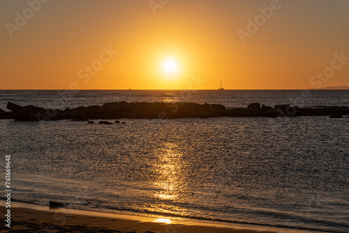 Fototapeta Naklejka Na Ścianę i Meble -  Orange sunset over ocean and reef with boat on horizon