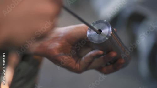 An employee is engaged in processing a metal product with a hand tool at the final stage of production at a production or metallurgical plant photo