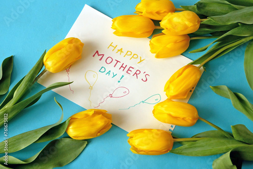 hands put a Happy Mother's Day card and flowers on the table, preparing for congratulations on Mother's Day