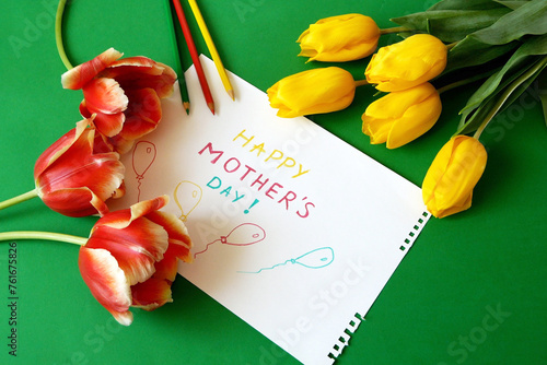 hands put a Happy Mother's Day card and flowers on the table, preparing for congratulations on Mother's Day