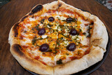 Traditional pizza. Top view of a mozzarella cheese pizza with tomato sauce, black olives and fresh oregano, on the wooden table.	